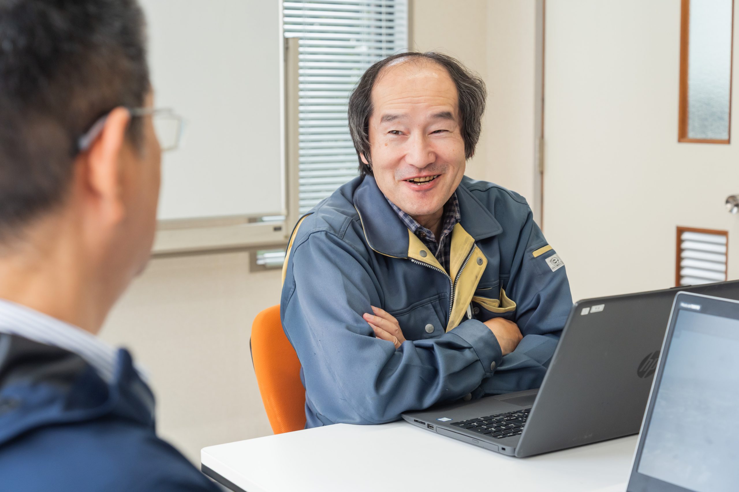 腕を組んで同僚と話すアークの社員