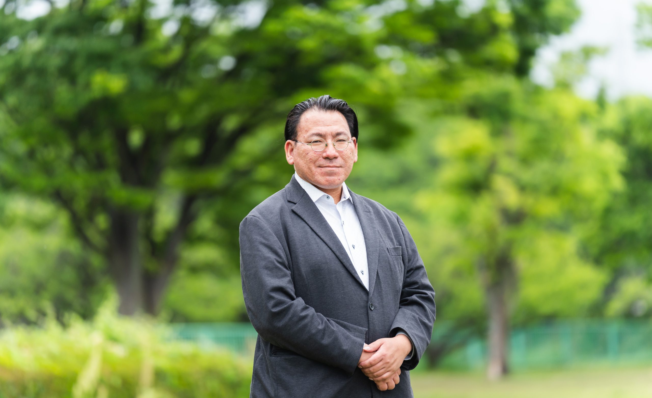 自然豊かな屋外で笑顔を見せる代表